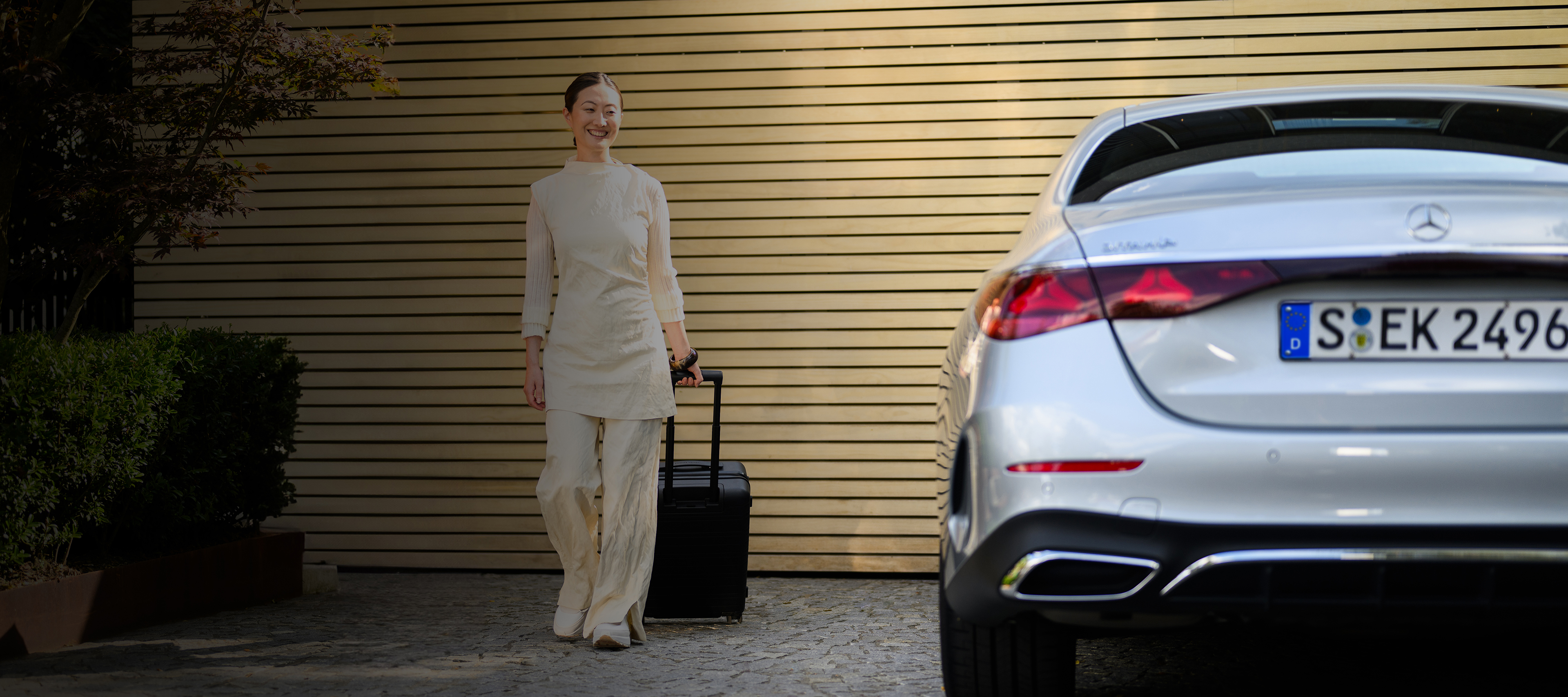 Ofertas | Servicios financieros | Mercedes-Benz Una mujer caminando con una maleta hacia su Mercedes-Benz
