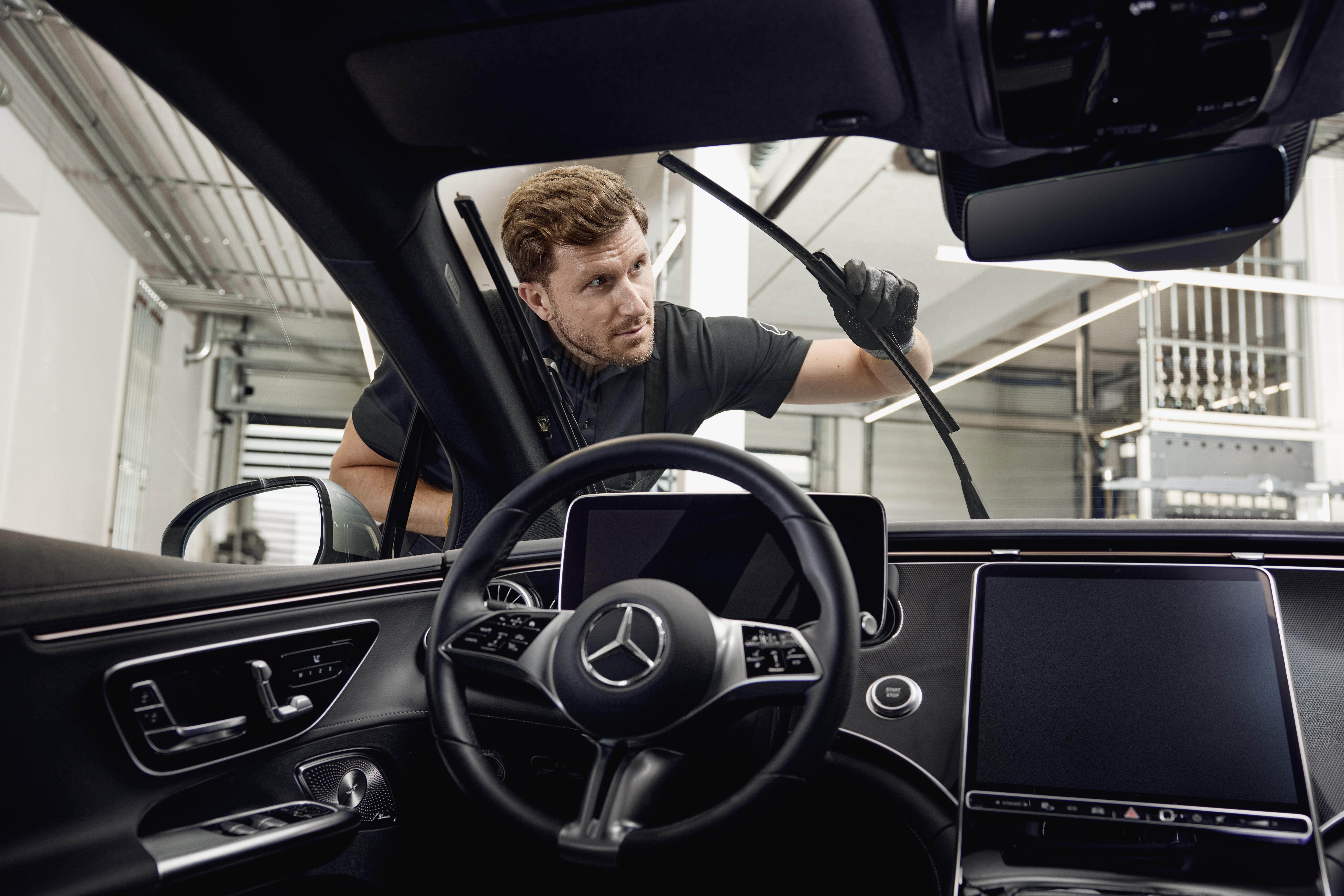 Escobillas limpiaparabrisas originales Mercedes-Benz Vista interior de un vehículo Mercedes-Benz con un técnico cambiando escobillas limpiaparabrisas originales.