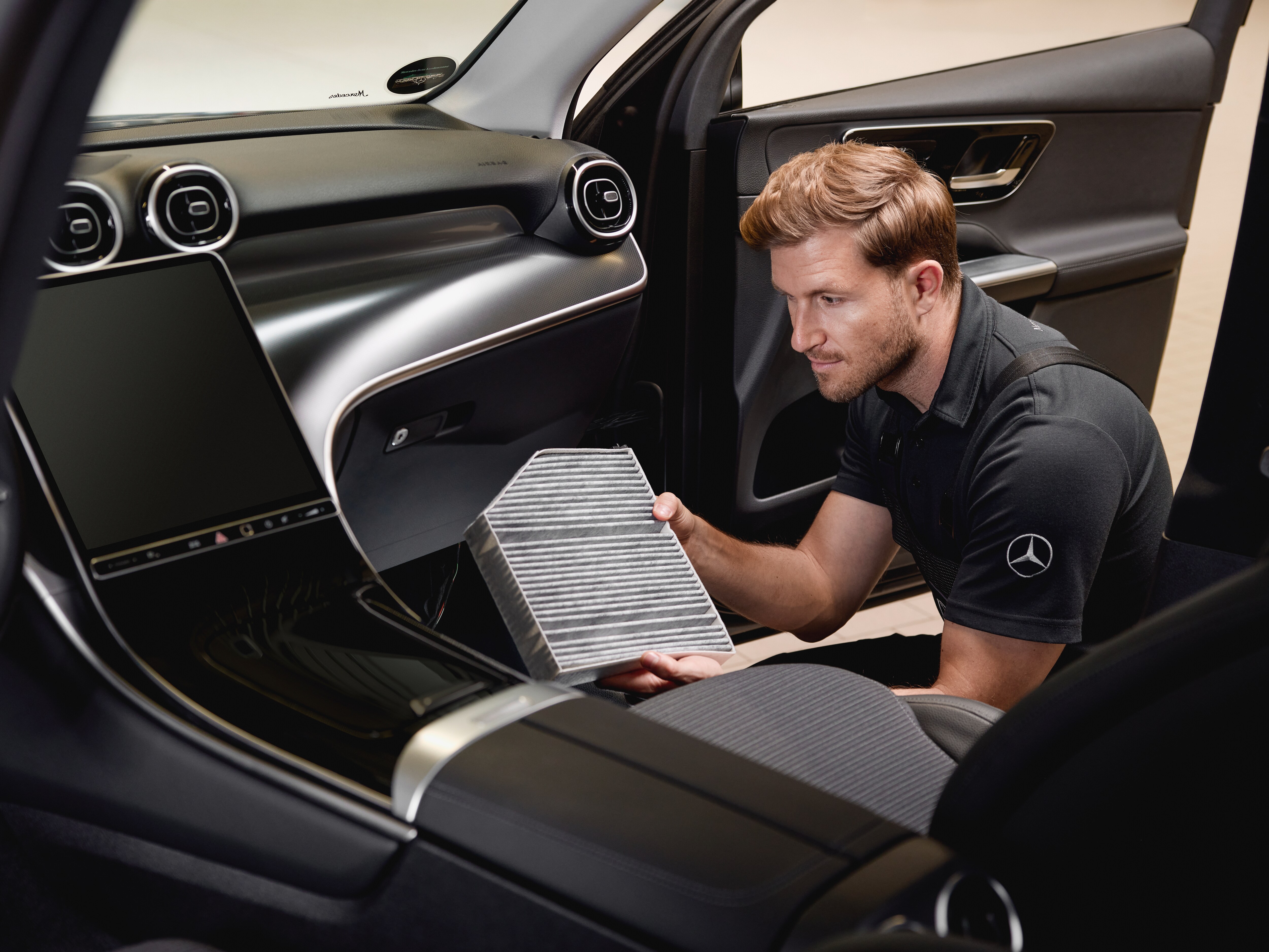 Operación de servicio interior mostrando la sustitución de un filtro de aire del habitáculo utilizando una pieza original Mercedes-Benz.