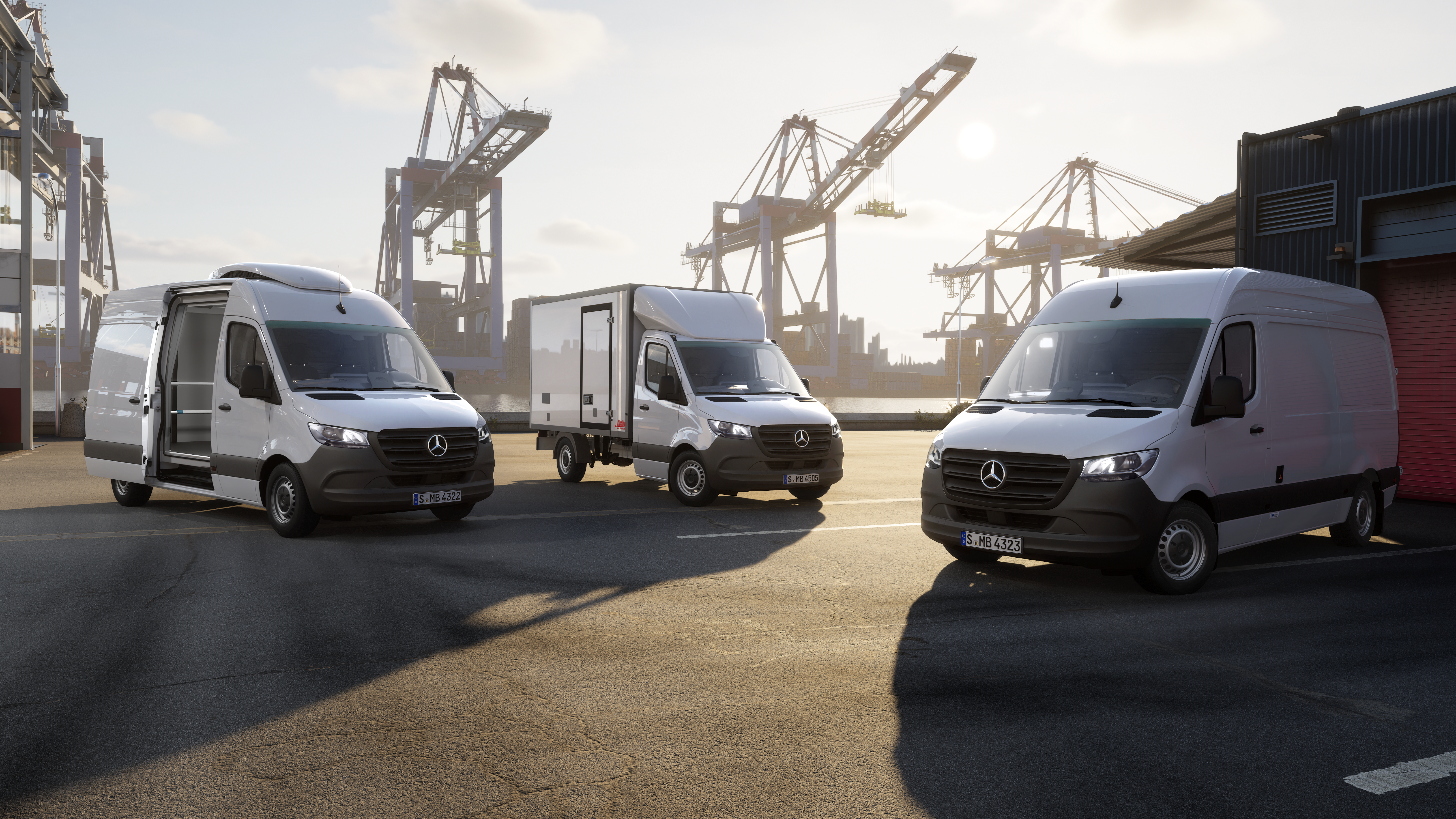 Furgonetas Mercedes-Benz en operaciones de CEP y logística en una moderna terminal de contenedores. Tres furgonetas Mercedes-Benz situadas en una terminal de contenedores con grúas portuarias: soluciones de vehículos eficientes para servicios de mensajería, exprés y logística.