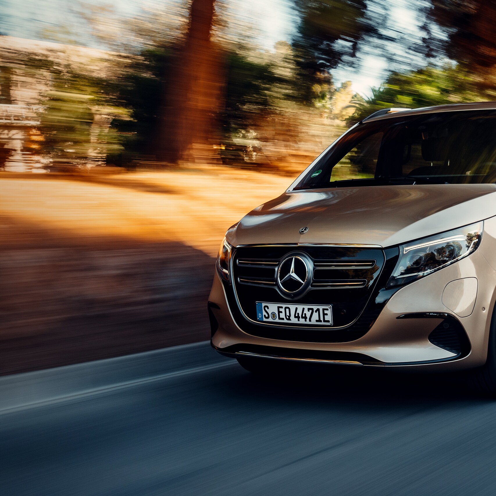 Una furgoneta Mercedes-Benz EQV dorada, circula por una carretera